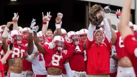 041214-CFB-huskers-bo-pelini-leads-team-out-of-tunnel-with-cat-ahn-PI.webp