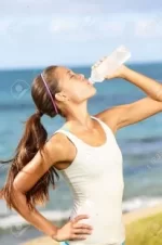 20560263-fitness-woman-drinking-water-after-running-at-beach-thirsty-sport-runner-resting-tak...webp